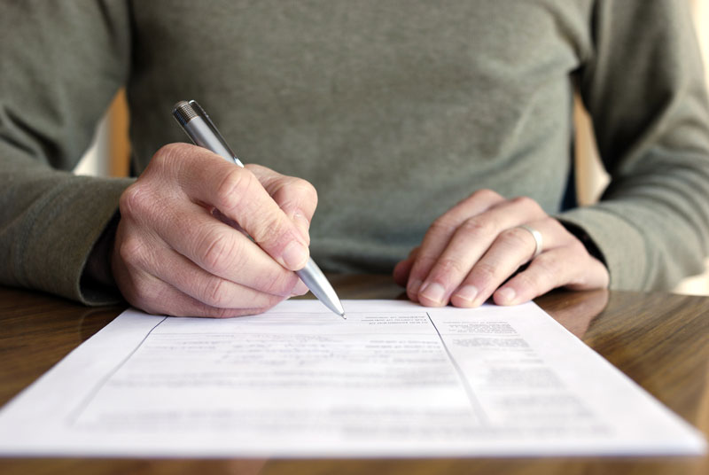 woman using a pen to sign a contract